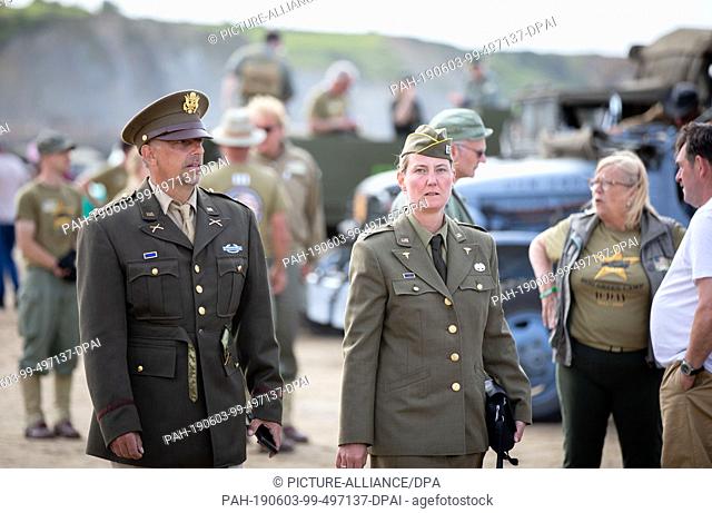 03 June 2019, France (France), Arromanches-Les-Bains: Bianca and Thomas Scherer from Bad Oldesloe in historical US uniforms from the Second World War walk...