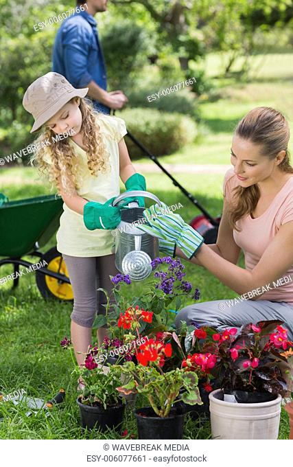 Mother with daughter watering plants