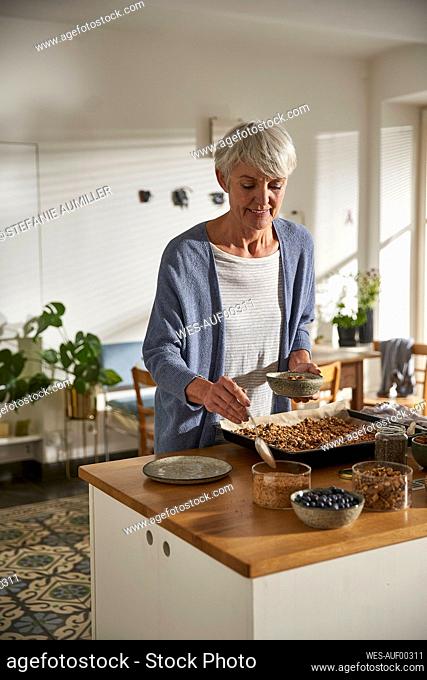 Smiling senior woman preparing granola