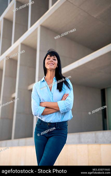 Mature smiling businesswoman standing with arms crossed