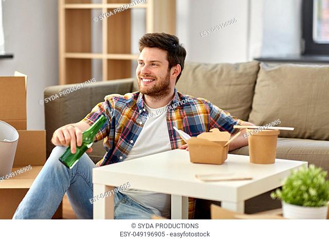 smiling man drinking beer and eating at new home