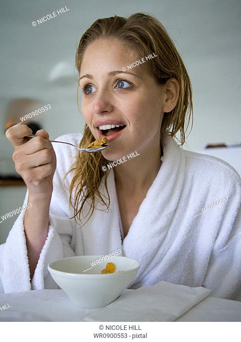 Woman in bathrobe eating cereal