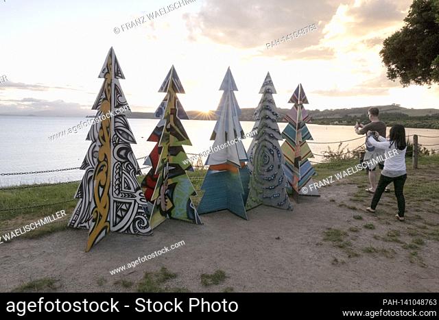 Artificial Weihaftertsbaeume (Weihaftertsbaume) on the shores of Lake Taupo, crater lake, caldera; two tourists take pictures of them; Prisoners in the sun on...
