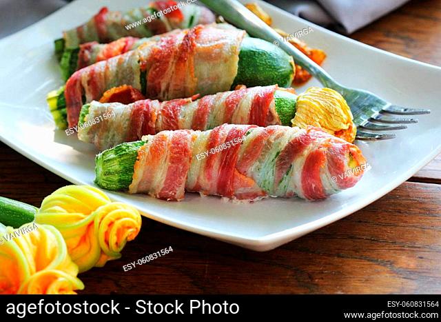 Grilled zucchini fries wrapped in a bacon on white plate