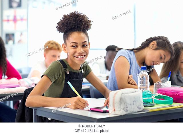 Portrait confident junior high school girl student doing homework in classroom