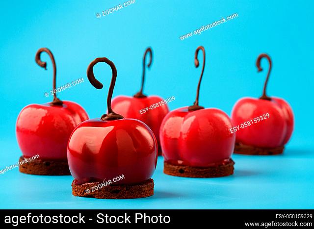 Glossy mousse cakes in the form of cherries on a blue background