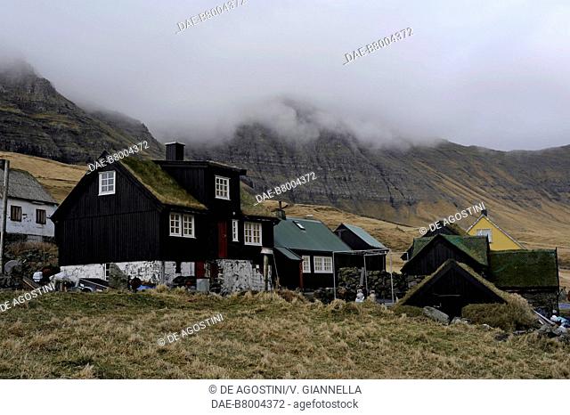 Wooden houses with grass covered roofs in Gasadalur village, low clouds, Vagar island, Faroe Islands, Denmark