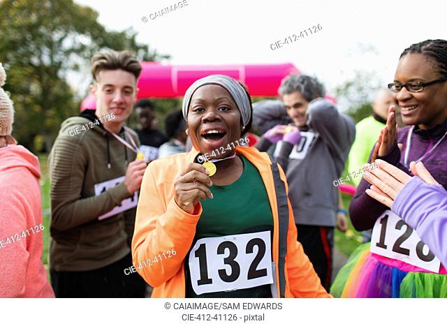 Portrait enthusiastic female runner showing medal at charity run