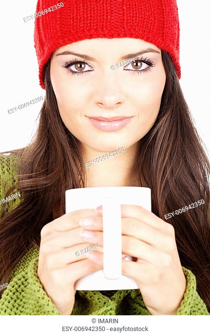 young brunette woman in wool sweater and cap holding a teapot, isolated on white