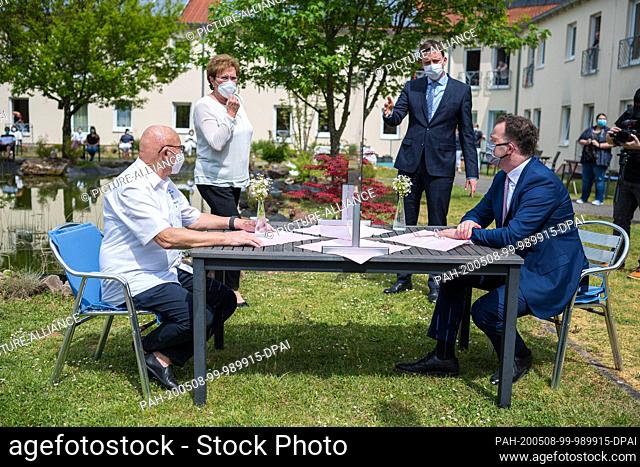 08 May 2020, Saarland, Neunkirchen: Federal Health Minister Jens Spahn (CDU, r) sits at a visitors' table with a Plexiglas pane when visiting the Annaheim old...