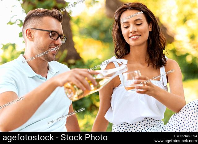 happy couple with wine having picnic at park