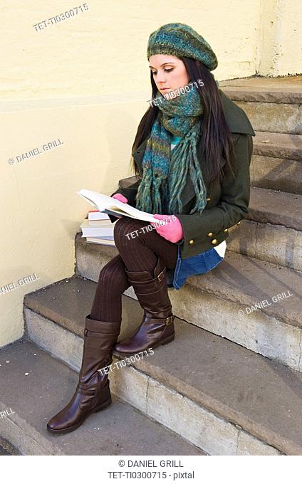 Woman reading book on steps