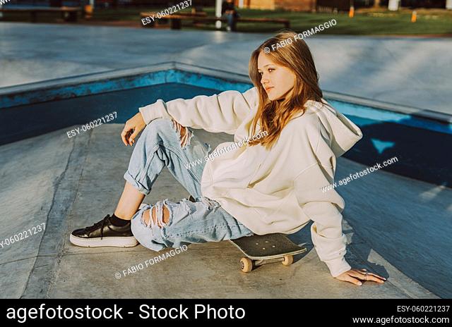 Stylish cool teen female skateboarder at skate park