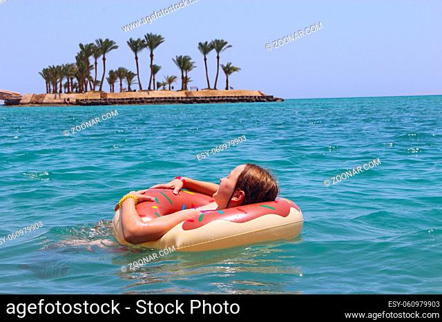 Little girl swimming in water lying on inflatable circle on summer holidays at sea. Rest on sea. Happy childhood in resort
