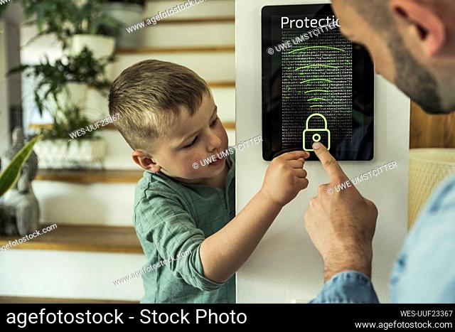 Boy with father touching digital tablet while unlocking in smart home