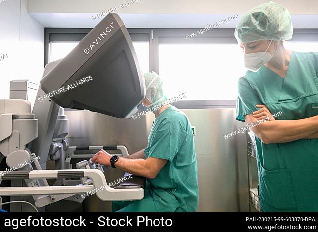 15 February 2023, Saxony, Dresden: Surgeon Sören Torge Mees (l) demonstrates the robotic console of the latest generation DaVinci surgical system during a press...