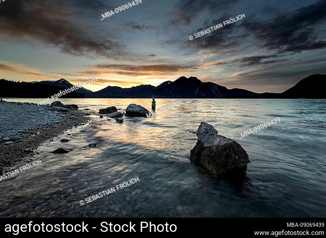 Stones and in the background Steinmandl on the shore of Walchensee during sunset. In the background the Bavarian Prealps with the Herzogstand