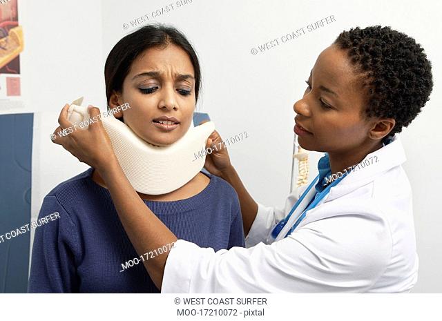 Female doctor puting brace on patient's neck