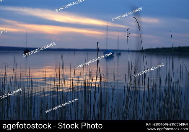 10 May 2022, Bavaria, Herrsching: Sailboats anchor on the Ammersee, which lies in the sunset. Photo: Karl-Josef Hildenbrand/dpa