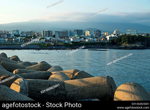 Cityscape with wavebreakers of Seogwipo with mount Hallasan in background, Jeju Island, South Korea