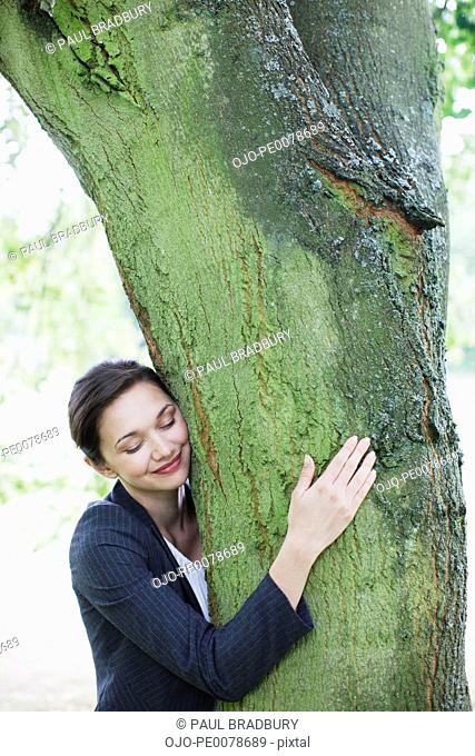 Businesswoman hugging tree