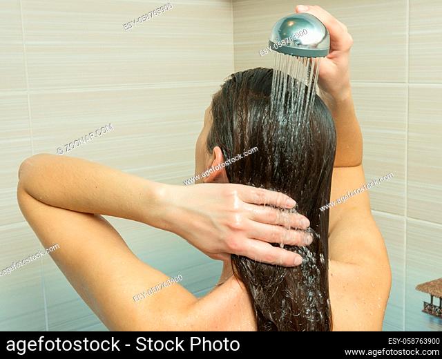 The girl washes her hair in the bathroom under the shower
