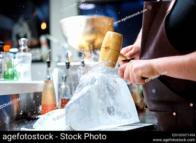 Bartender mannually crushed ice with wooden hammer and metal knife