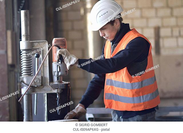 Factory worker using drill in concrete reinforcement factory