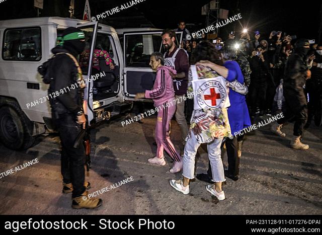 28 November 2023, Palestinian Territories, Rafah: Hamas and Islamic Jihad fighters hand over newly released hostages to the Red Cross in Rafah