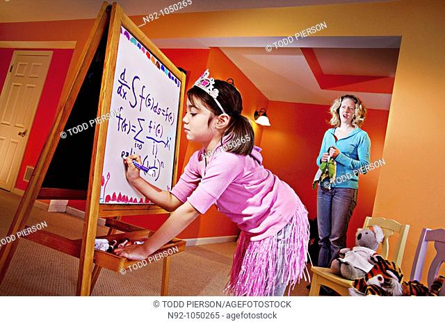 Little girl, age 6 writing on board and mom standing by in awe