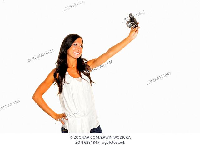 Eine junge Frau hat Spaß während sie sich selber mit einem alten Fotoapparat fotografiert. Selfie