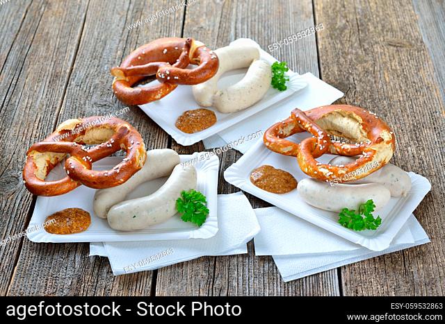Streetfood bayerisch: Zwei frische Weißwürste mit süßem Senf und Breze auf Pappteller serviert - Bavarian snack: Two white sausages with a fresh pretzel and...