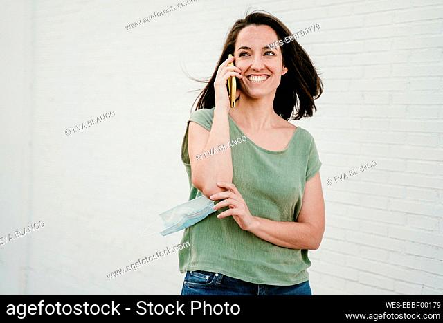Portrait of happy woman on the phone with protective mask