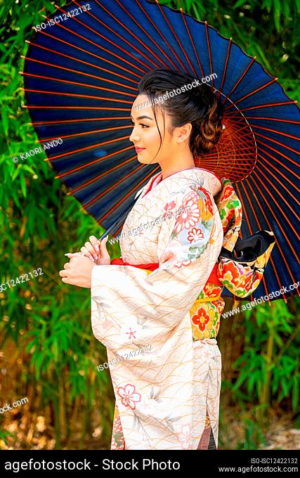 Pensive woman wearing kimono and holding parasol