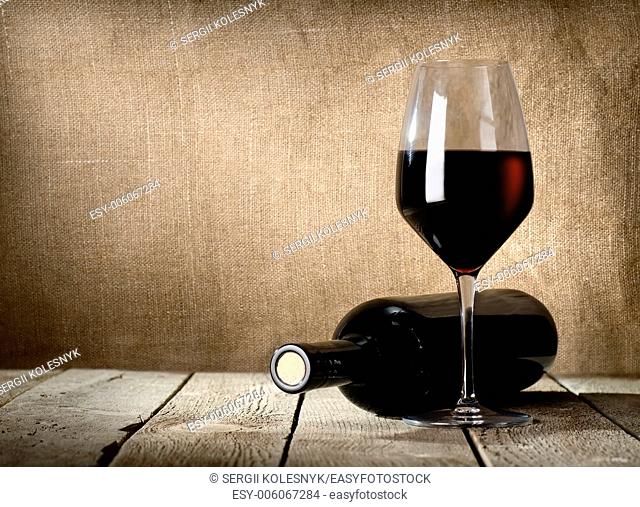 Black bottle of wine and wneglass on the background of the canvas