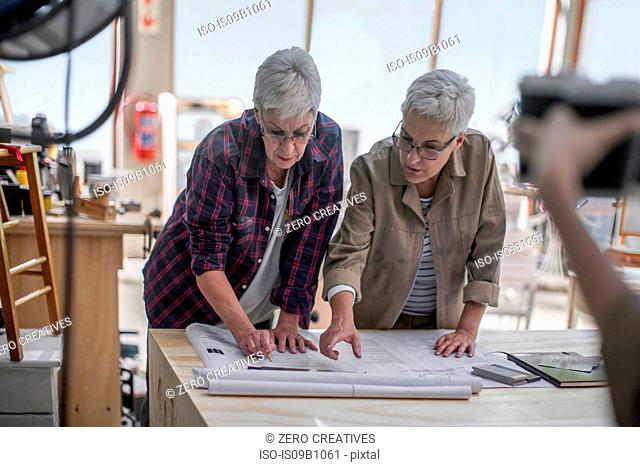 Female carpenters discussing blueprint in furniture making workshop