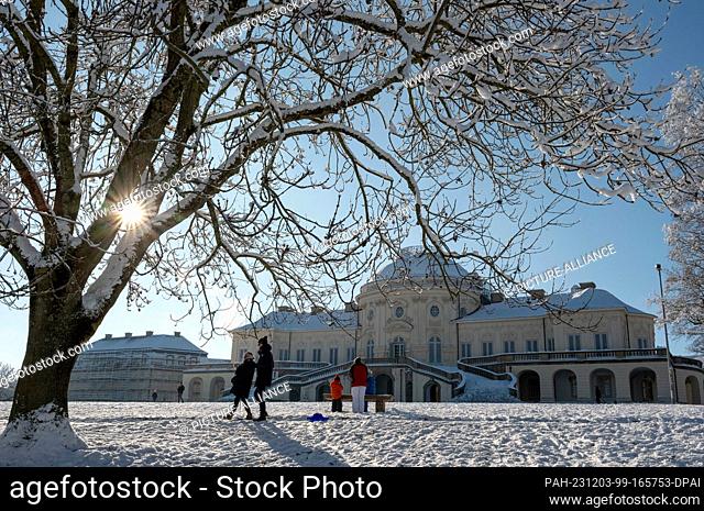 03 December 2023, Baden-Württemberg, Stuttgart: People enjoy the sunny winter weather while taking a walk in front of the snow-covered Solitude Palace