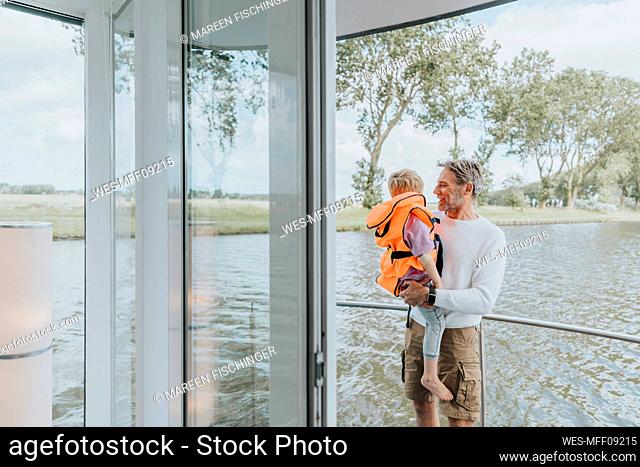 Son with father standing by railing in balcony