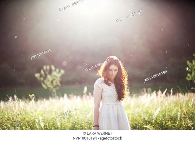 Young woman standing on a meadow in backlight, portrait