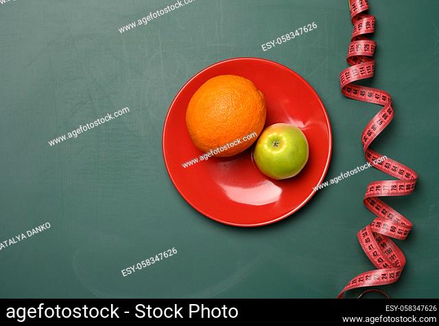 green apple and red round plate, red measuring tape on a green background, weight loss concept, flat lay