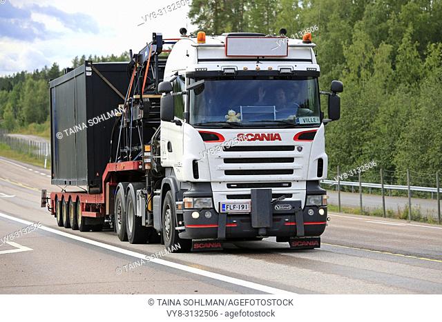 Orivesi, Finland - August 27, 2018: White Scania truck hauls wide container on trailer along highway in Central Finland on overcast day