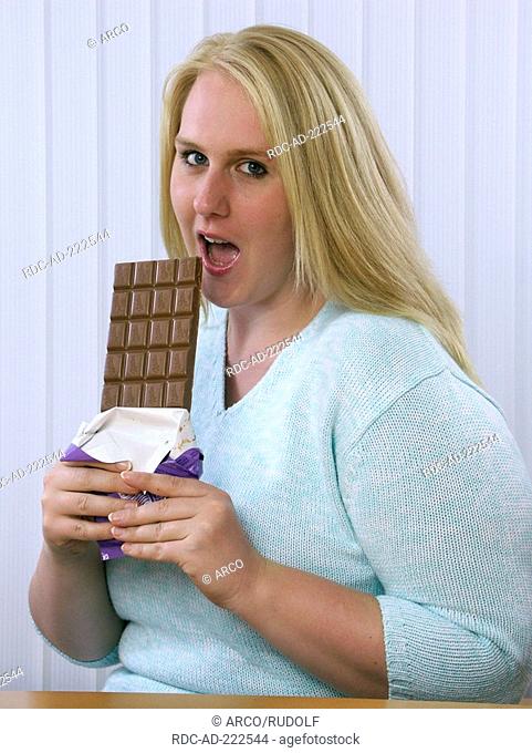 Woman taking a bite of bar of chocolate