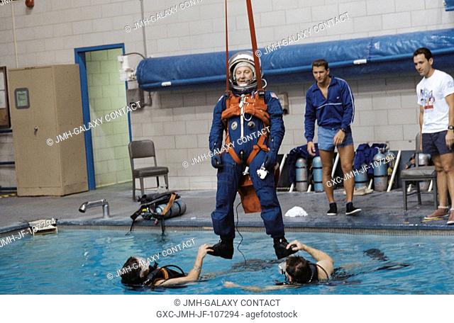 Payload specialist Albert Sacco Jr. is assisted by two SCUBA-equipped divers as he hangs by his parachute harness