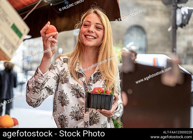 Young woman buying fruits at market stall