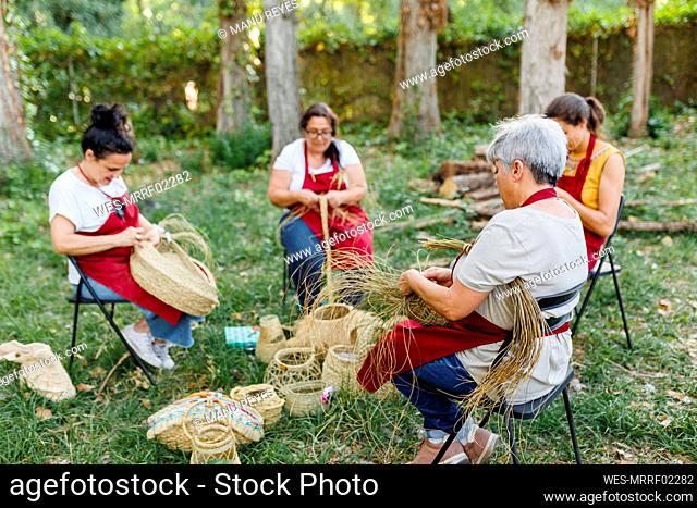 Artisan with coworkers weaving esparto grass in garden
