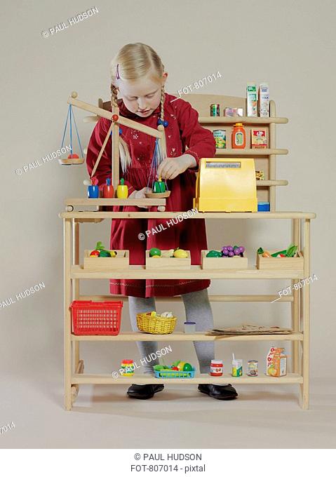 A girl playing in a children's wooden grocery store