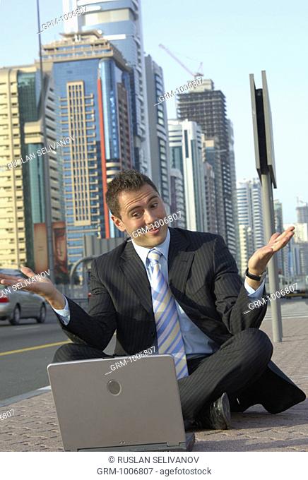 Businessman sitting in tailor seat with laptop on Shaikh Zayed Road in Dubai