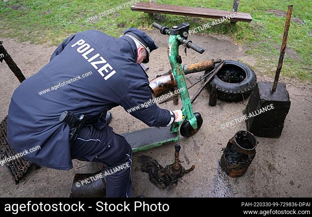 30 March 2022, Hamburg: A police officer checks an e-scooter found by divers during the ""trash dive"" in the Alster. During the city cleaning campaign...