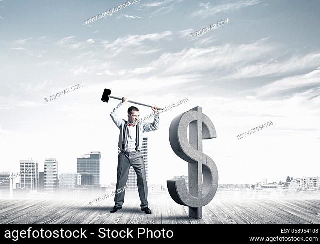 Young furious businessman going to crash with hammer stone dollar symbol