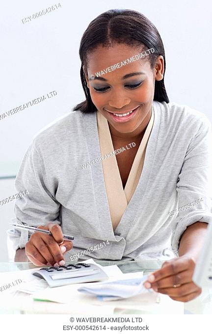 Smiling businesswoman using a calculator at her desk in the office